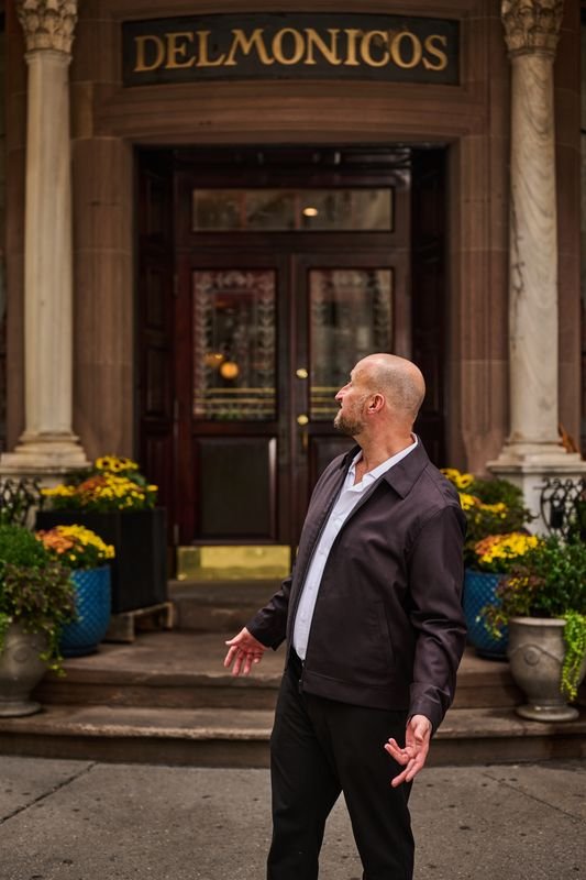 Dennis Turcinovic outside Delmonico's, looking up at the carved sign above the entrance