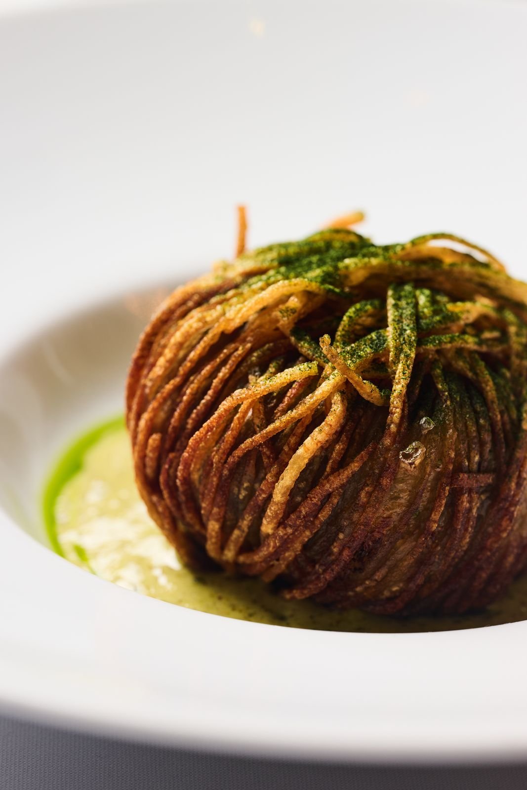 A golden, crisp-layered potato on a white plate at Delmonico's