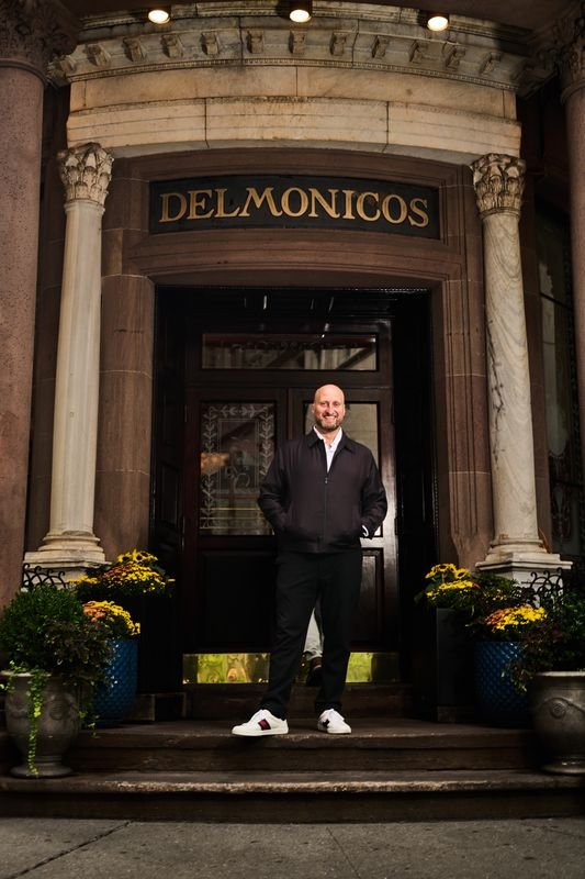 Dennis Turcinovic standing beneath the carved Delmonico's entrance on Beaver Street